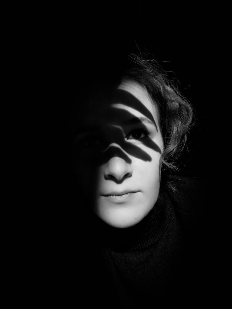 Black and white portrait of a woman with dramatic light and shadow play across her face.