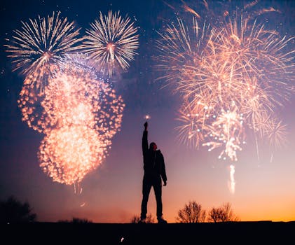 A person celebrates under vibrant fireworks in the evening sky in Kragujevac, Serbia.
